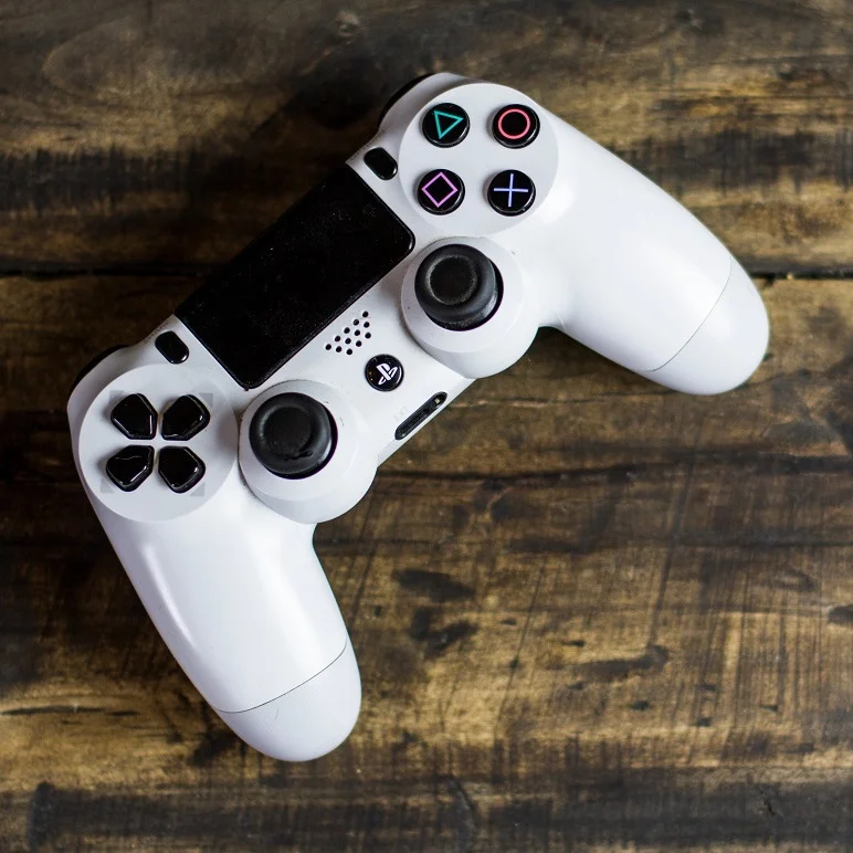 White Sony Ps4 dualshock on wood table. Stock image from Pexels.