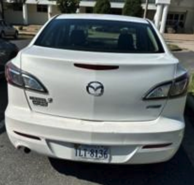 Rear view of a white Mazda sedan showing the logo, taillights, and trunk badge.