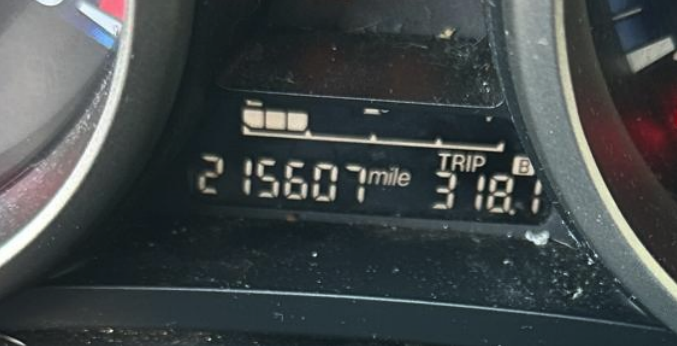 Digital car dashboard display showing an odometer reading of 215,607 miles and trip B reading of 318.1.