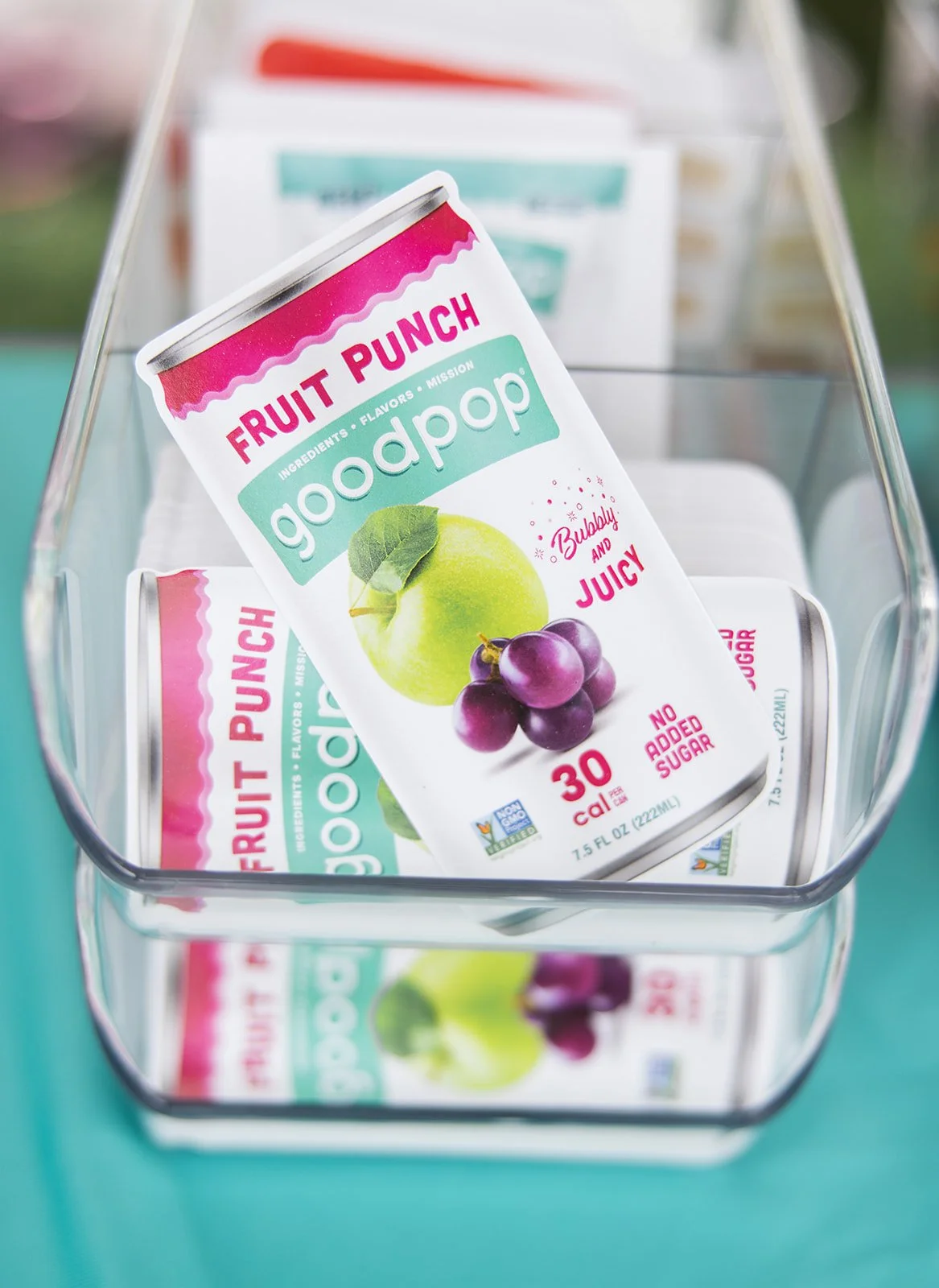 Close-up of a can of goodpop fruit punch popsicle in a glass container, with other cans in the background.