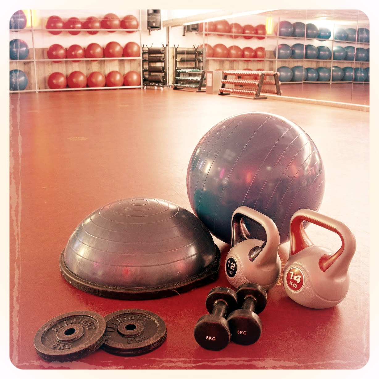 Fitnessmaterialen: kettlebells, dumbbells, een fitbal, een Bosu en schijven voor een barbell.