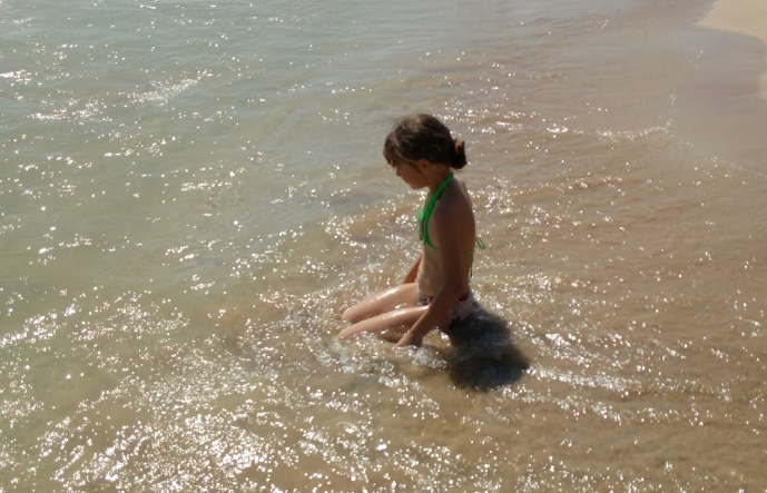 strand meisje zit in water cropped out.jpg
