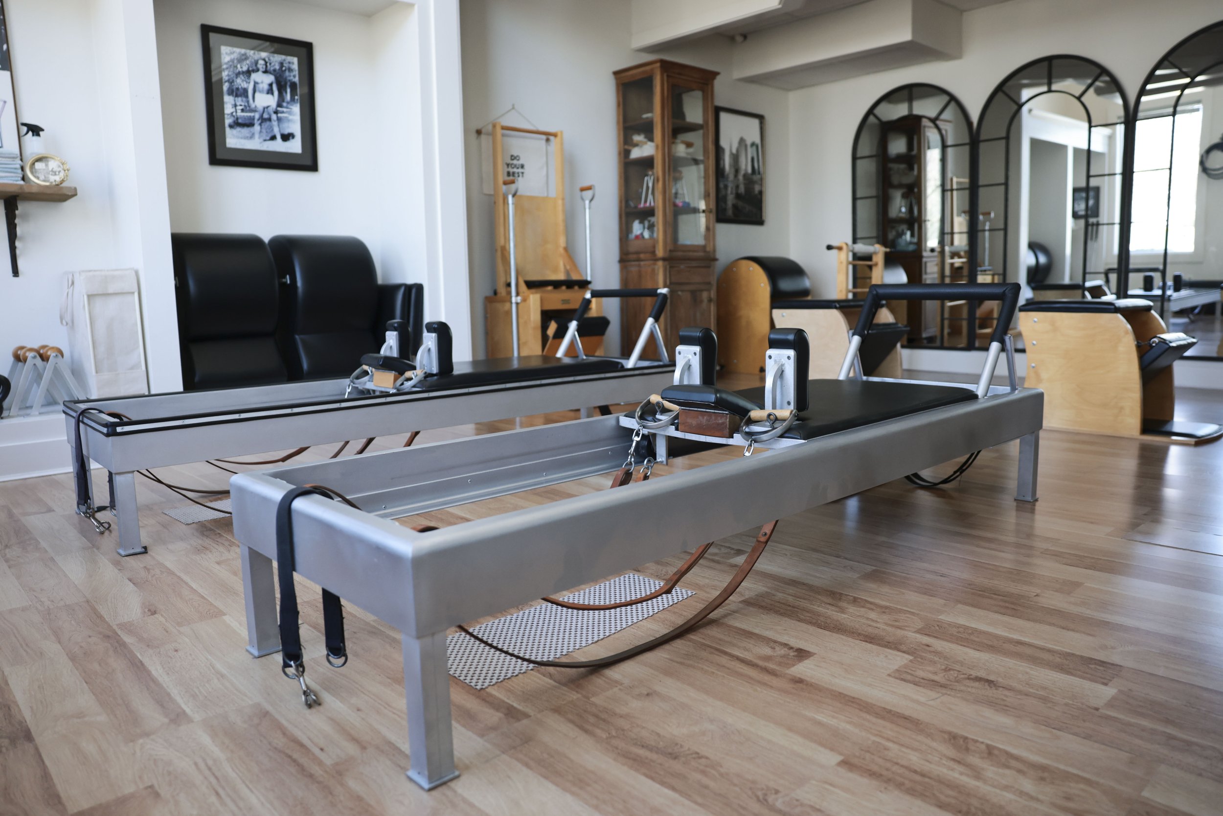 Pilates reformer equipment in a fitness studio with mirrors on the wall.