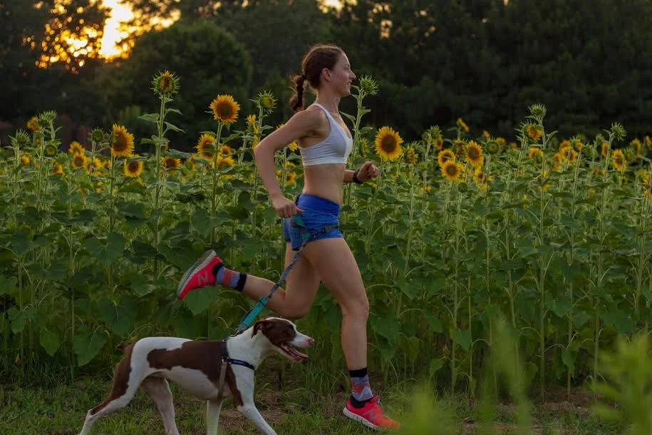 Erin and her dog Charlie running through the sunflower field at Dorothea Dix Park