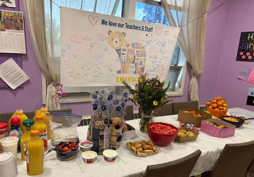 A table covered with snacks for the teachers with a signed poster saying we love our teachers & staff
