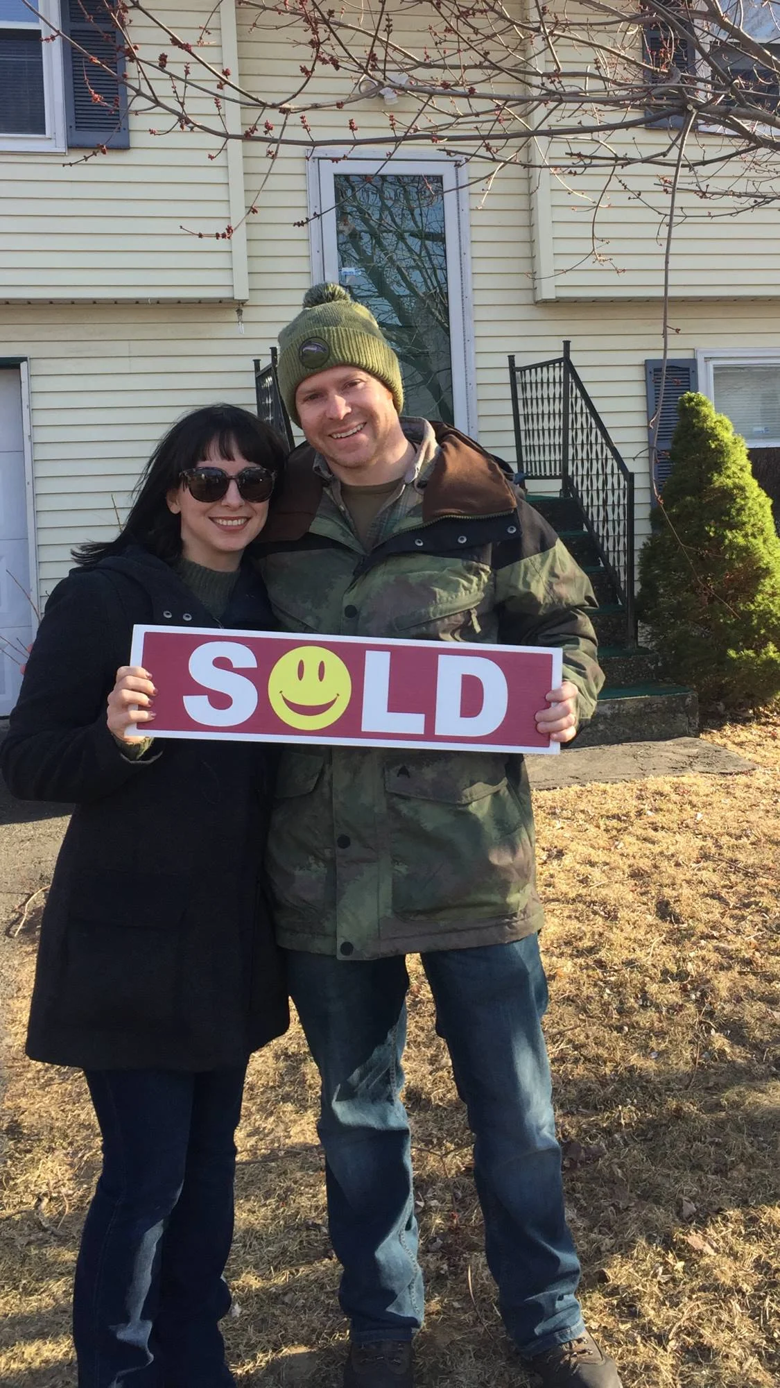 Clients holding a SOLD sign in front of their new home.jpg