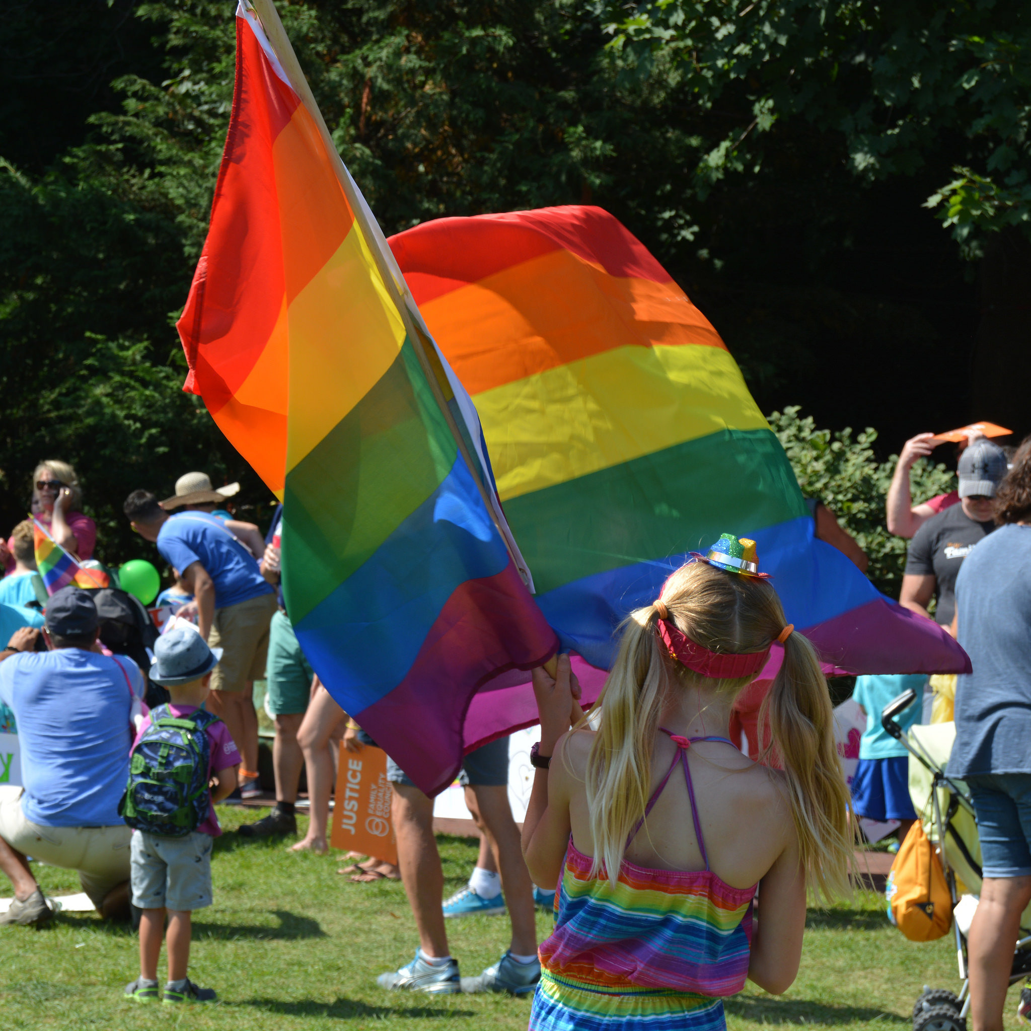 kiddo in a rainbow shirt holding a big pride flag at Pride Parade prep
