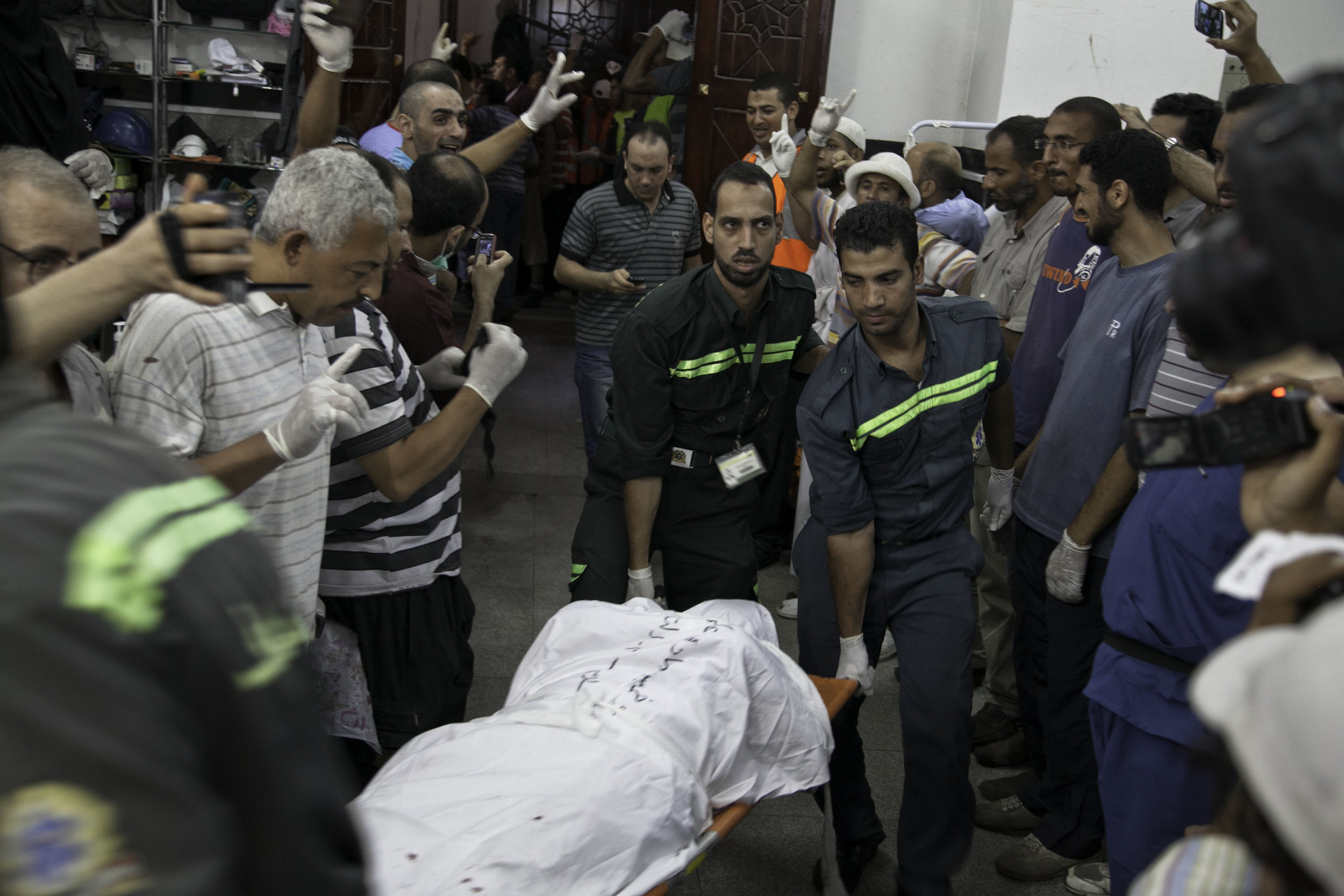 Early morning scores of pro-Morsi supporters were killed and hundreds injured by security forces at Raba'a al Adawiya on July 26, 2013, causing more division between anti and pro-Morsi supporters. Ambulance workers take the bodies out of a makeshift hospital.