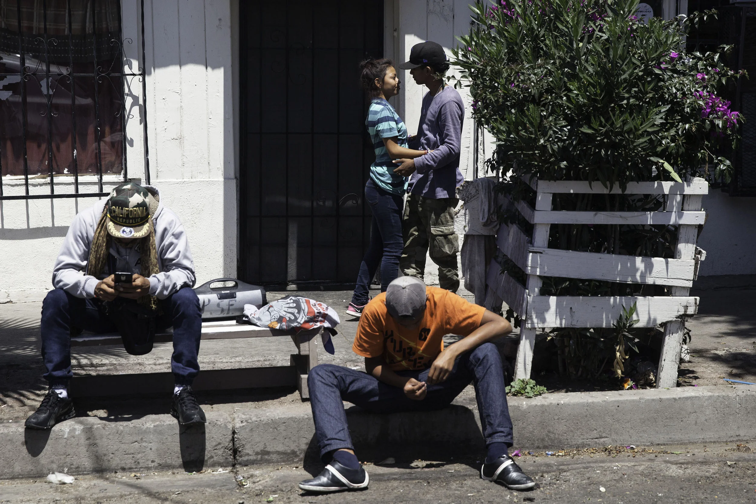 Teenagers from Central America who are staying at Juventud 2000 shelter in Tijuana, MX, hang out across the street listening to Guns and Roses on April 25, 2018.