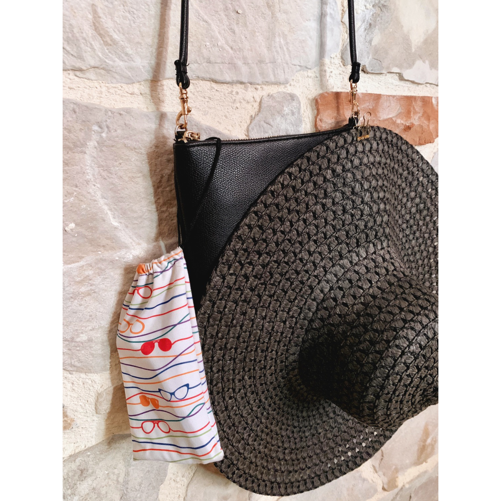 Upclose image of hat &amp; sunglasses hanging from small purse