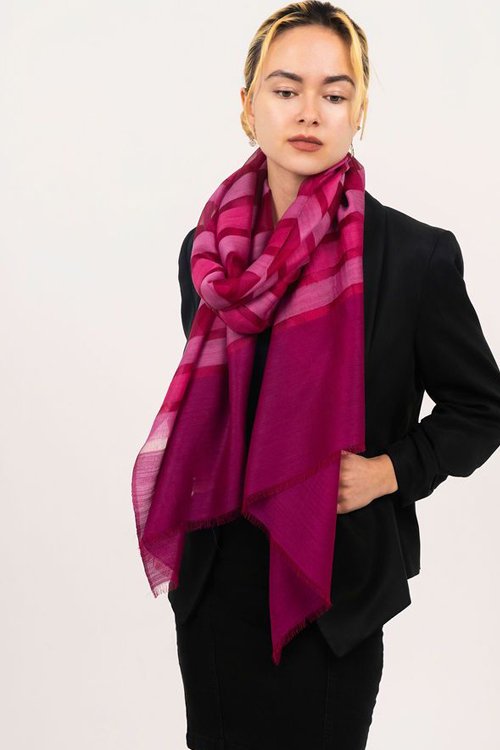 Woman wearing the pink  colour variant of the Mae wool and silk striped scarf from DLUX