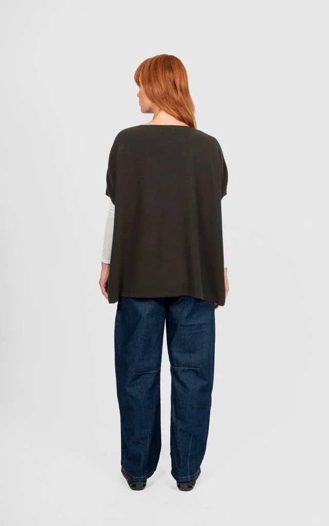 Back view of a woman wearing the Seed Stitch Poncho from Bridge and Lord in the olive green colour variant