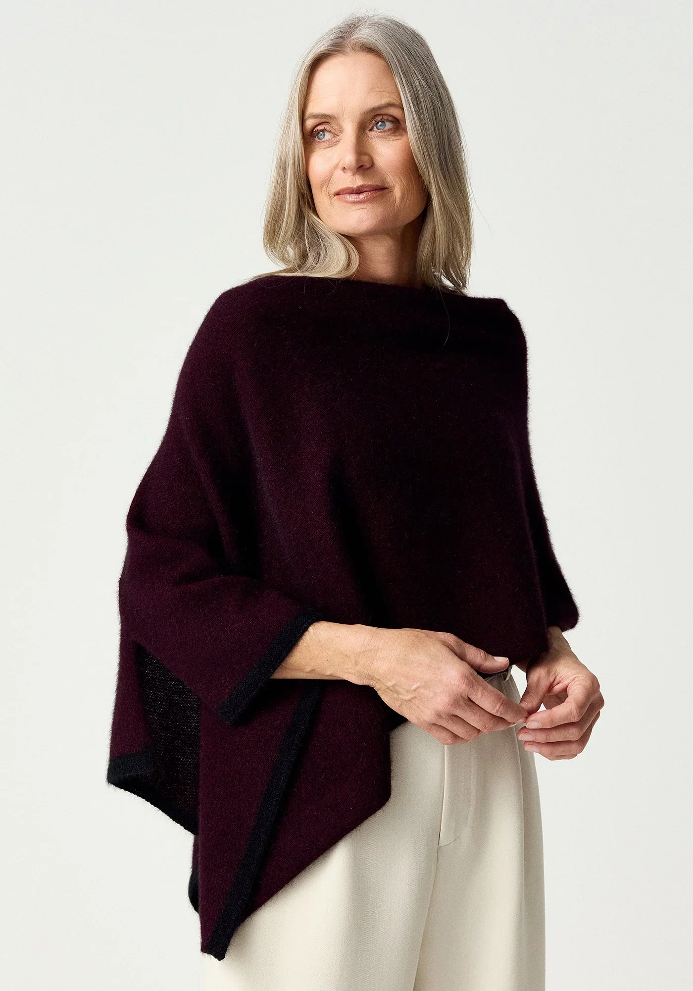 Woman wearing the Beetroot (dark purple) colour variant of the MerinoMink Two-tone Poncho made from Merino Wool and Possum Fur feather