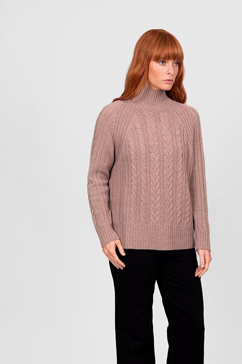 Woman wearing the cobblestone (deep beige) colour variant of the Cable Raglan Pullover from Bridge & Lord.