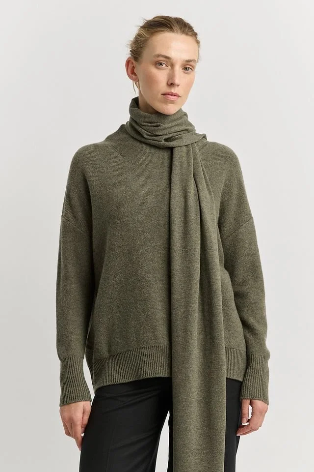 Woman wearing the Kale (olive green) colour variant of the Toorallie Extra Fine Wool Scarf made from 100% Merino lambswool)