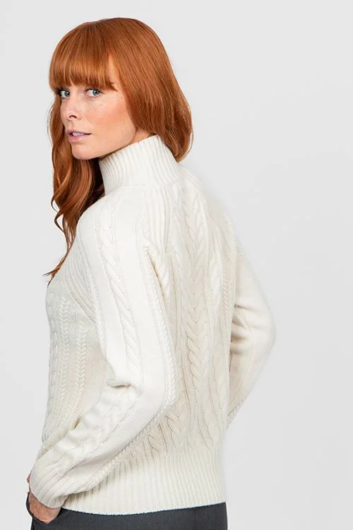 Woman wearing the ivory colour variant of the Cable Raglan Pullover from Bridge & Lord, with an easy view of the back cables.