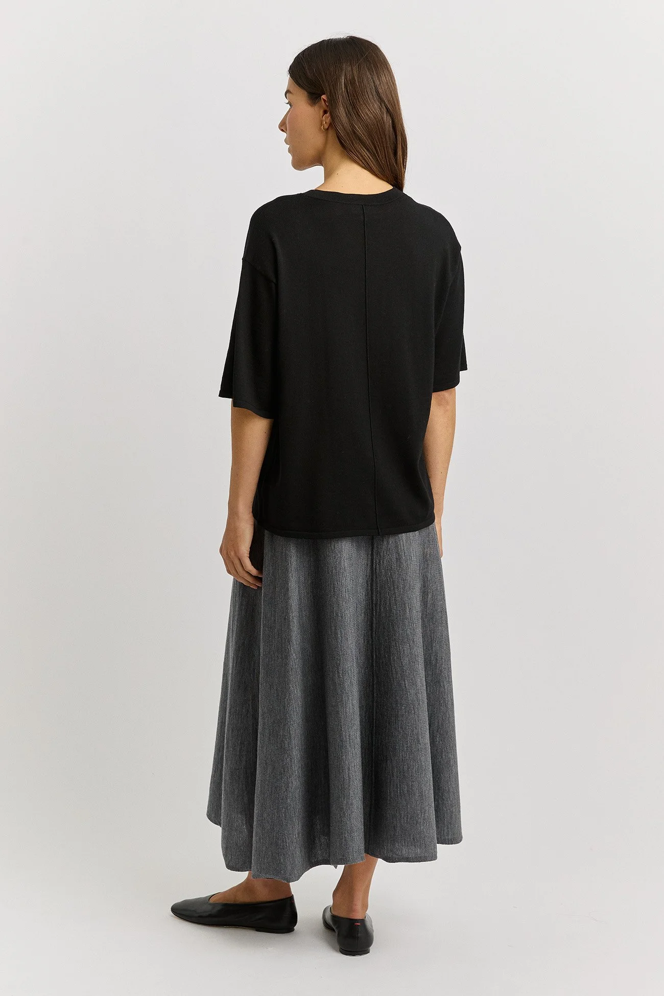 back view of a woman wearing the black colour variant of the Extra Fine Relaxed Knit Tee  made from 100% Merino Wool by Toorallie