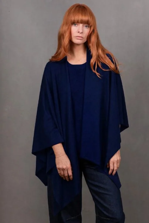 Woman wearing the Ink blue colour variant of the Wrap Topper made from Merino wool and cashmere from Bridge & Lord