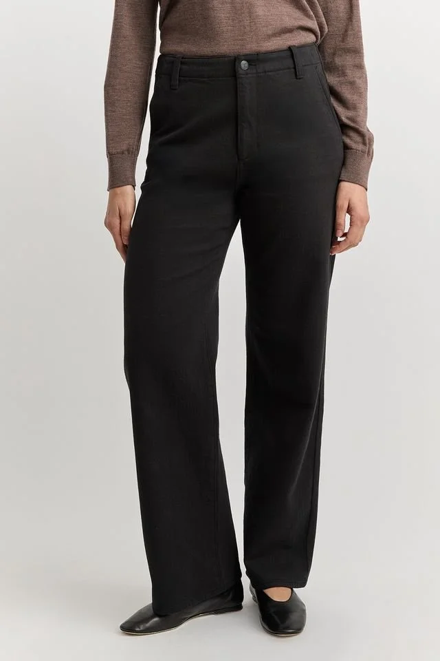 Closeup of the black version of the Toorallie Wide-leg-merino-denim jean worn by a woman.