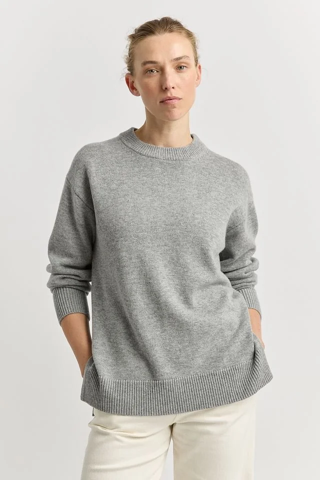 Woman wearing the Light Ash colour variant of the Toorallie Relaxed Longline Crew Sweater made from 100% Merino lambswool