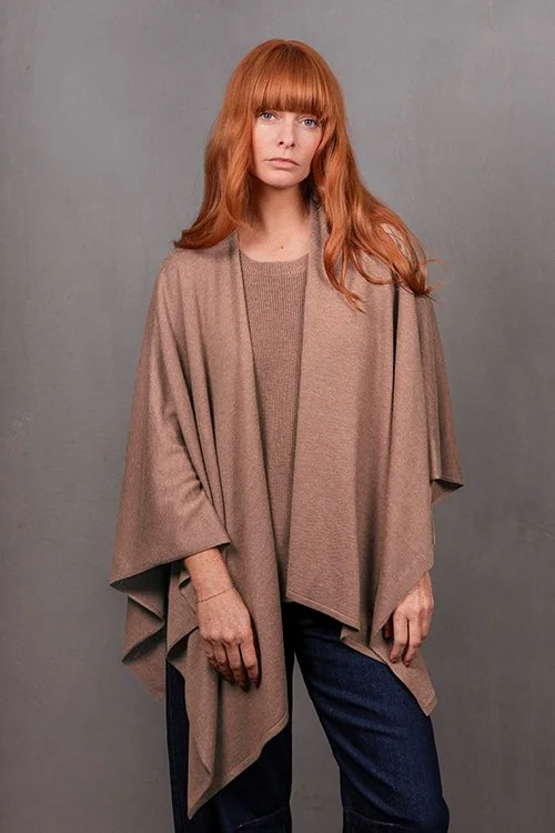 Woman wearing the Cobblestone beige colour variant of the Wrap Topper made from Merino wool and cashmere from Bridge & Lord