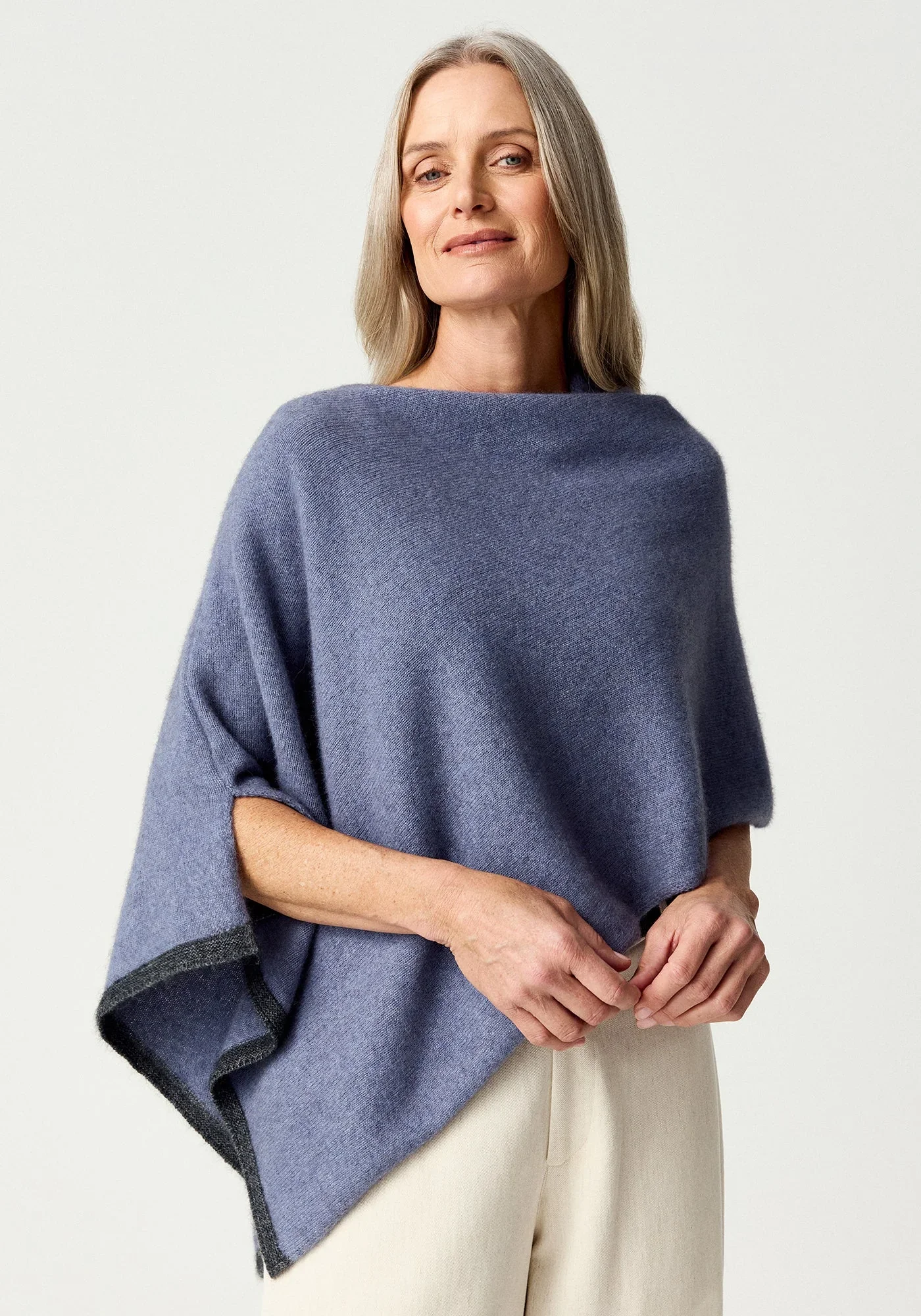 Woman wearing the Waterfall (dusky lilac) colour variant of the MerinoMink Two-tone Poncho made from Merino Wool and Possum Fur feather