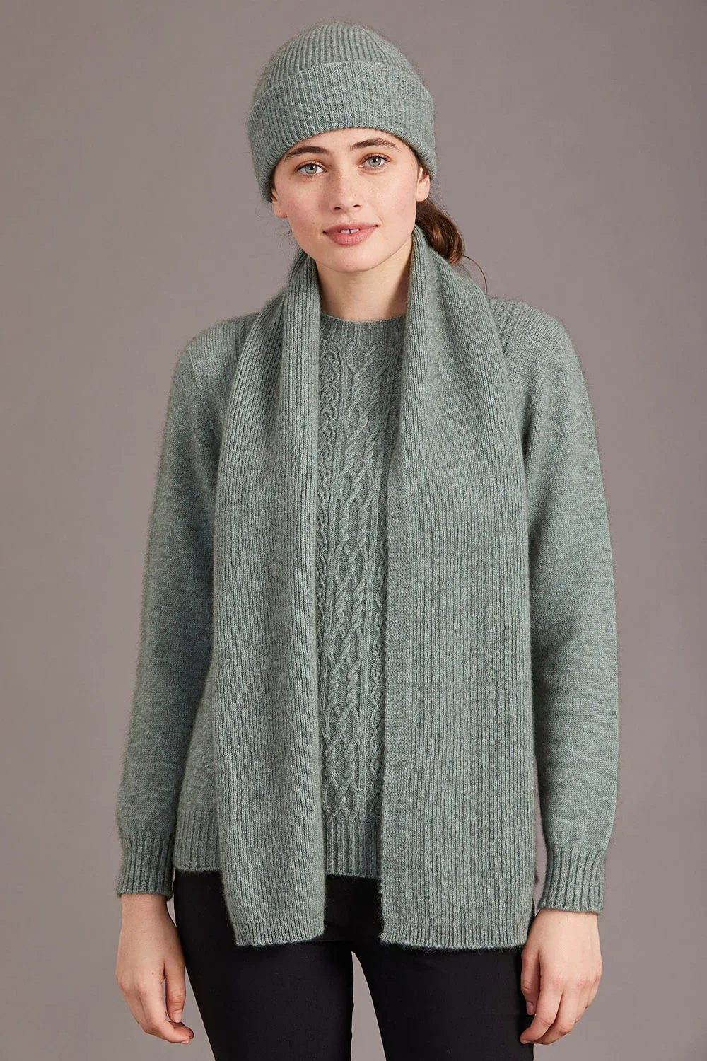 Woman wearing the McDonald Textiles fine rib scarf in the mint (light green) colour variant.