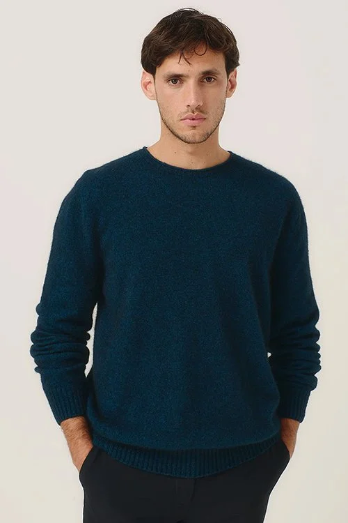 Man wearing the Merinomink Classic Crew Sweater made from Merino wool and Possum Fibre in the Peacock blue/green colour variant