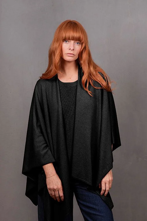 Woman wearing the Black  colour variant of the Wrap Topper made from Merino wool and cashmere from Bridge & Lord