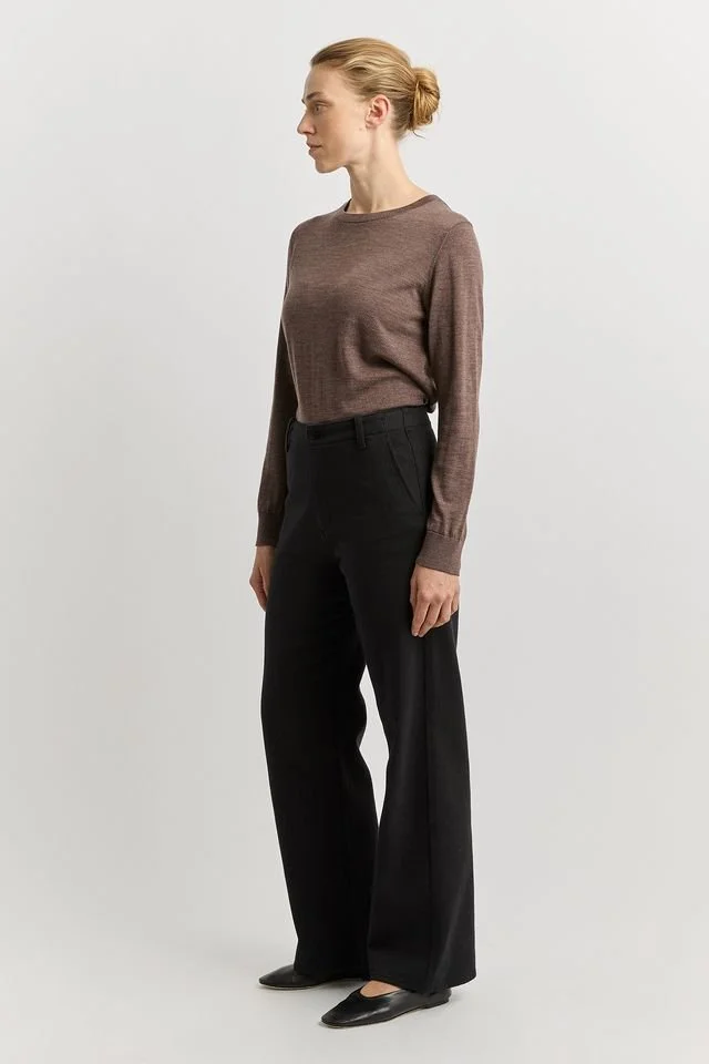 Side view of the black version of the Toorallie Wide-leg-merino-denim jean worn by a woman.