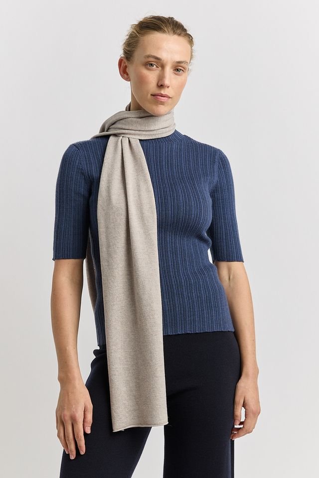 Woman wearing the light oat (pale beige) colour variant of the Toorallie Extra Fine Wool Scarf made from 100% Merino lambswool)