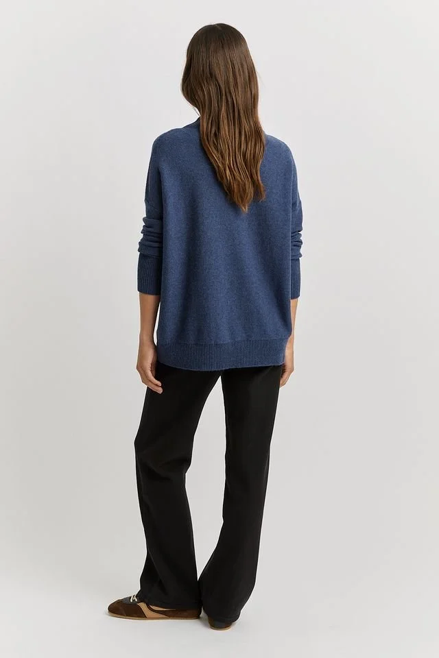 Back view of a woman wearing the Galaxy Blue colour variant of the Toorallie Drop Shoulder Mock Neck Sweater made from 100% Merino lambswool)