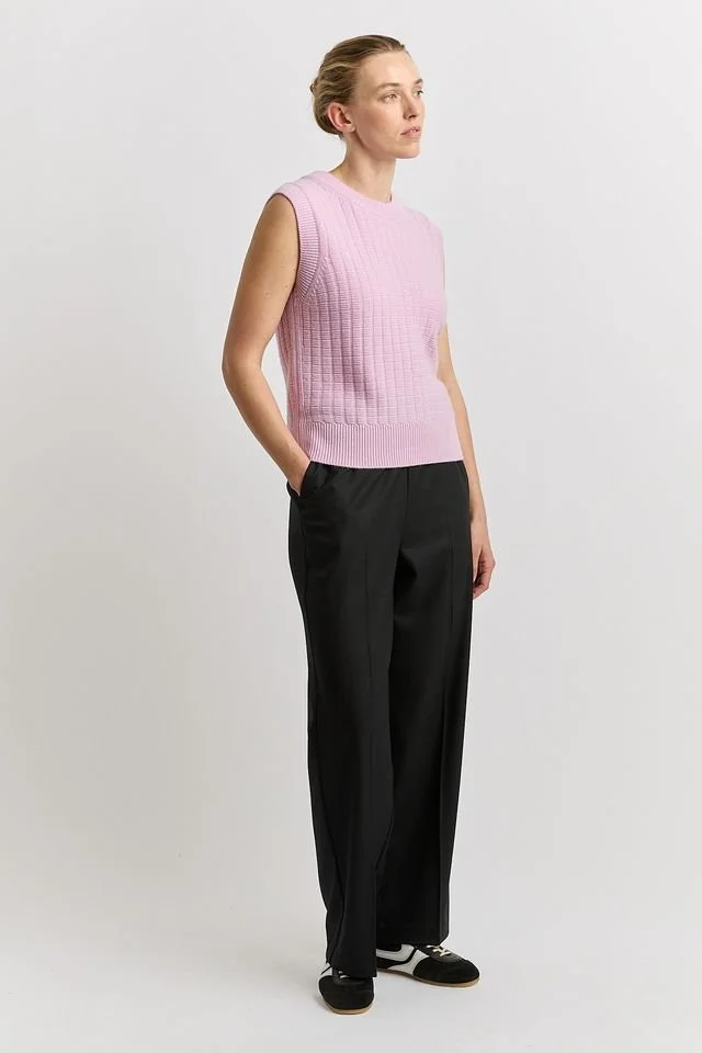 Woman wearing the powder pink variant of the Toorallie Toorallie Grid Knit Vest, made from Merino Lambswool.