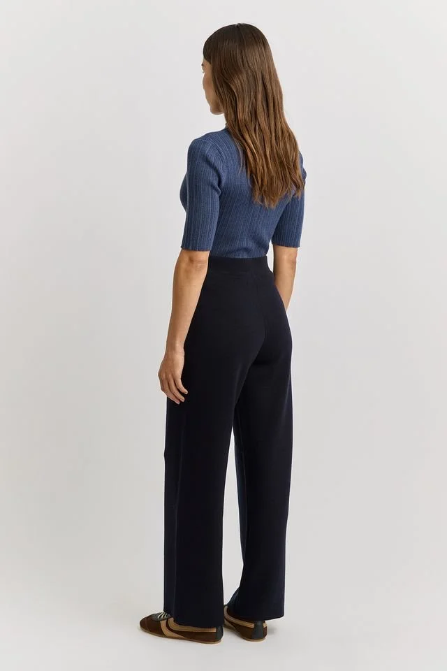 Back view of a woman wearing the navy blue colour variant of the Toorallie Knit Pant made from Australian Merino wool.