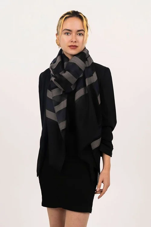 Woman wearing the black striped colour variant of the Mae wool and silk striped scarf from DLUX