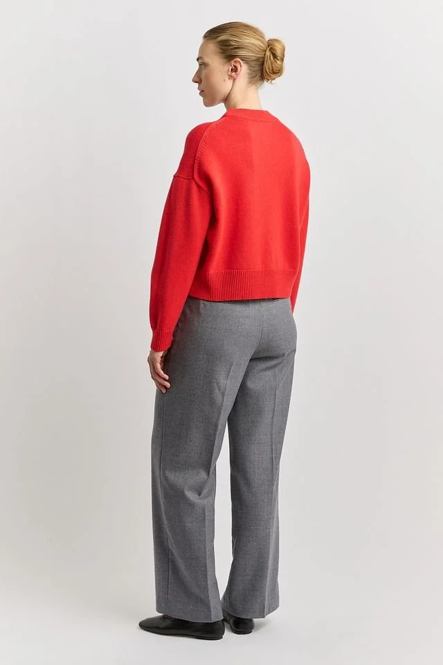 Back view of a woman wearing the Poppy red colour variant of the Toorallie Drop Shoulder Crew Neck Sweater made from 100% Merino lambswool)