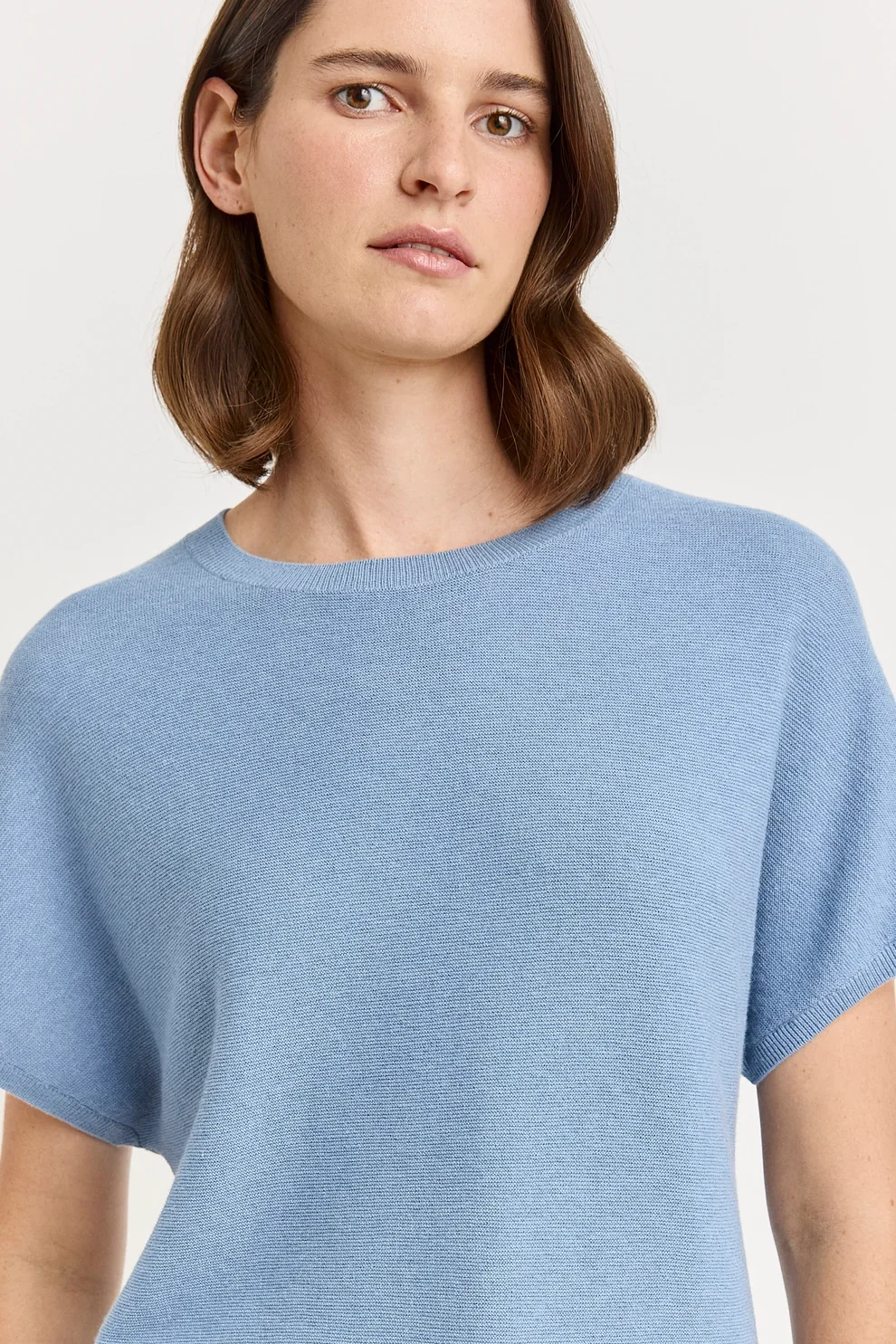 Woman wearing the Mist ( blue) colour variant of the Toorallie Links Cap Sleeve Top made from Organic Cotton and Merino