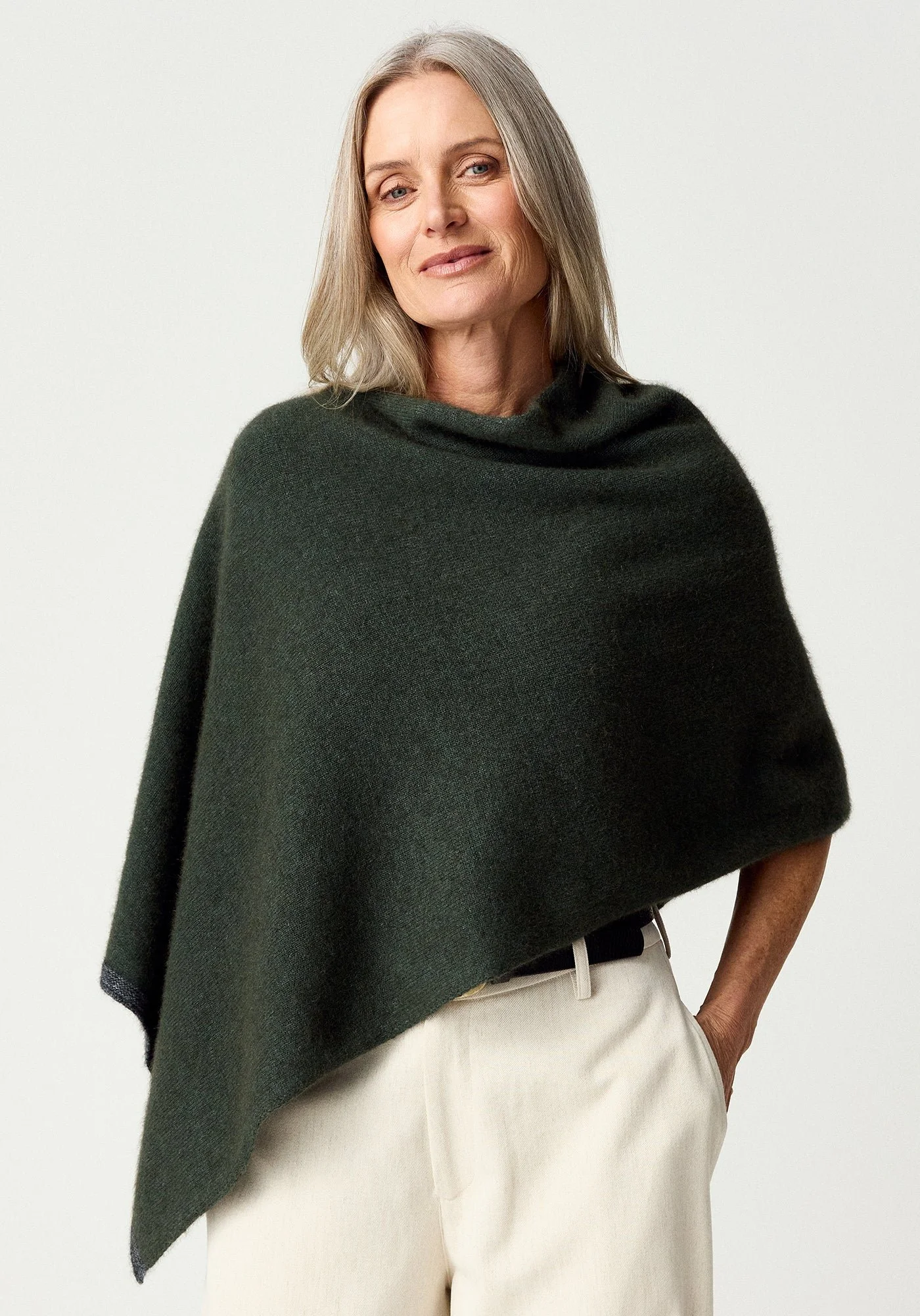Woman wearing the Wilderess (dark green) colour variant of the MerinoMink Two-tone Poncho made from Merino Wool and Possum Fur feather