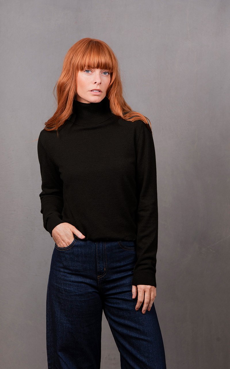 Woman wearing the black green colour variant of the Bridge & Lord roll neck pullover
