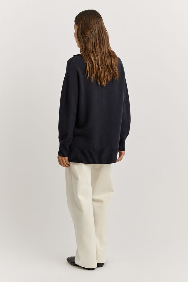 Back view of a woman wearing the Navy blue colour variant of the Toorallie Relaxed Longline Zip Polo Top made from 100% Merino Lambswool