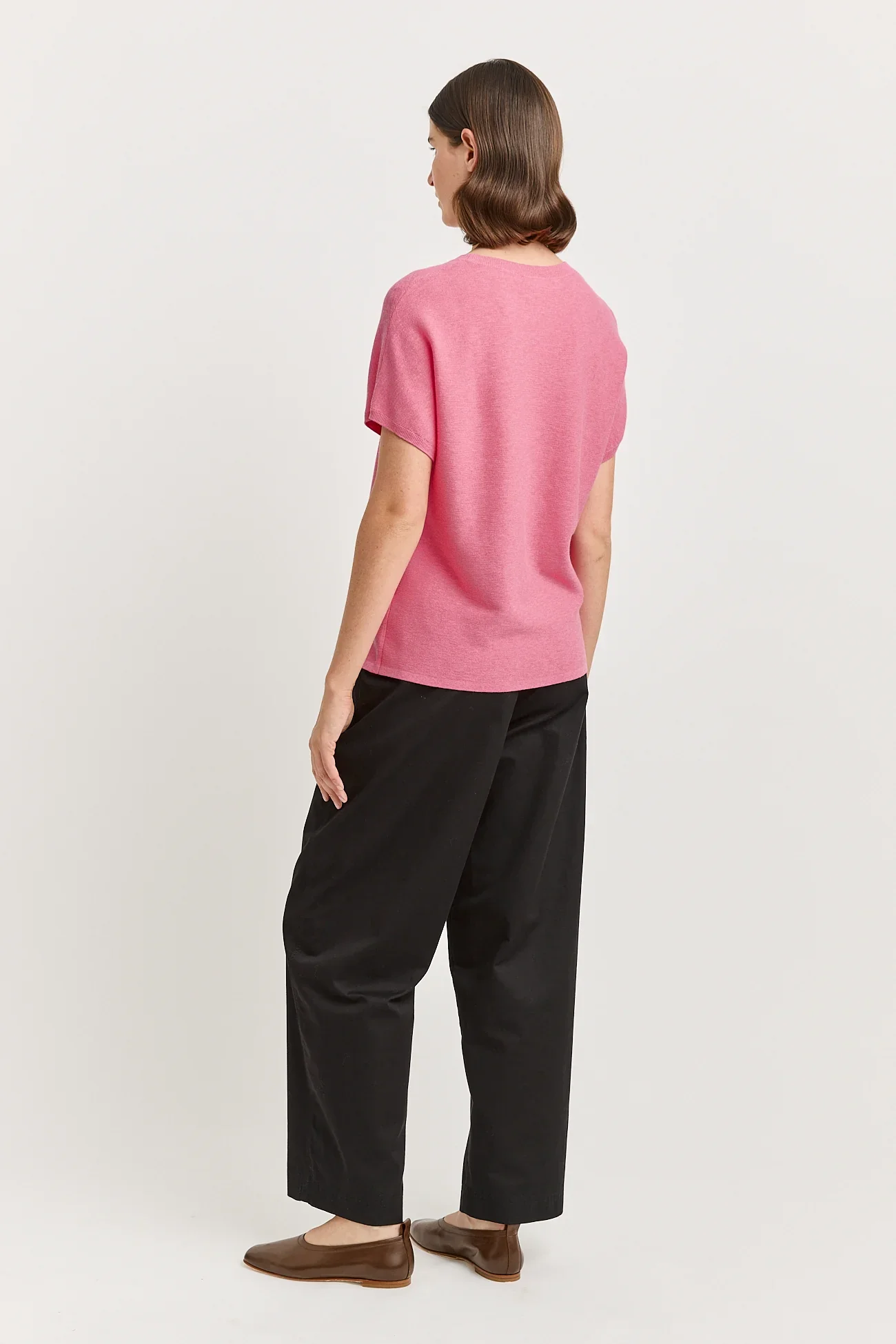 Back view of a woman wearing the Flamingo ( pink) colour variant of the Toorallie Links Cap Sleeve Top made from Organic Cotton and Merino