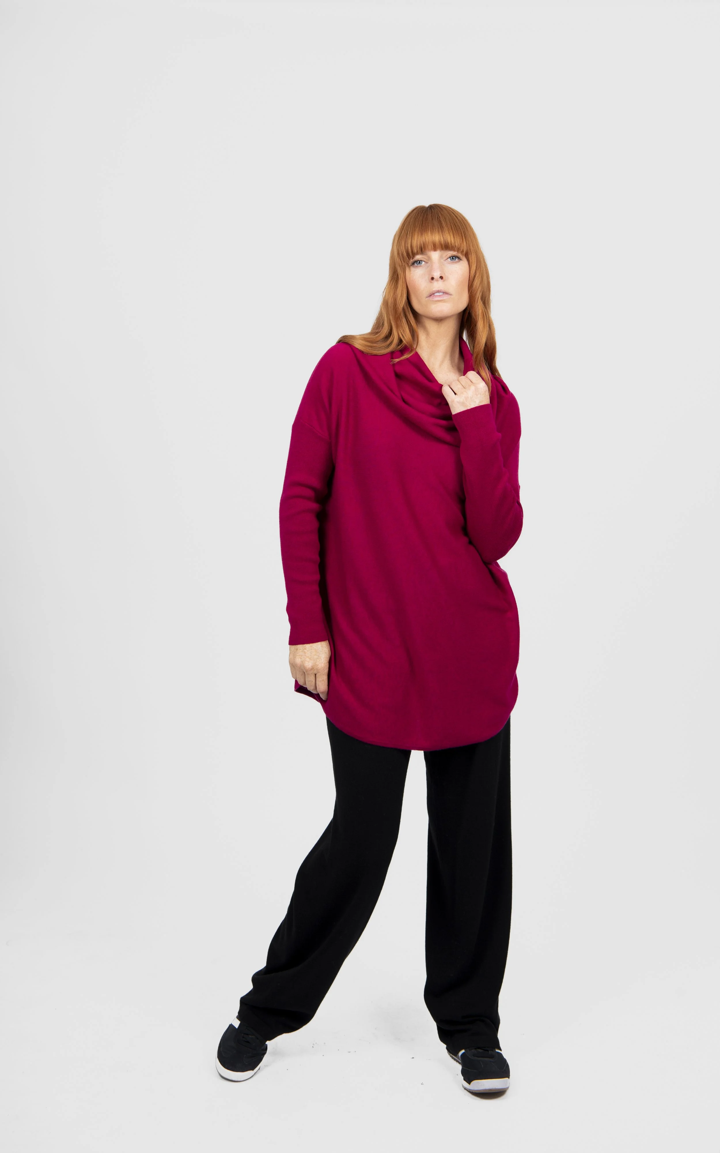 Woman wearing the Cassis (rich crimson) colour variant of the Bridge & Lord — Essential Curved Hem Cowl Neck Jumper made from Merino wool & Cashmere.