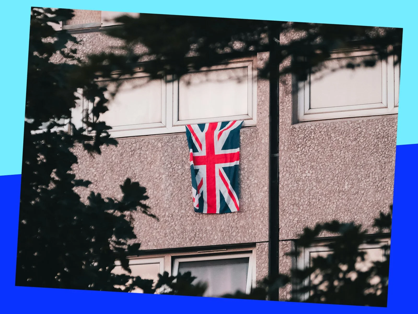 A Union Jack flag hangs from the window of a block of flats