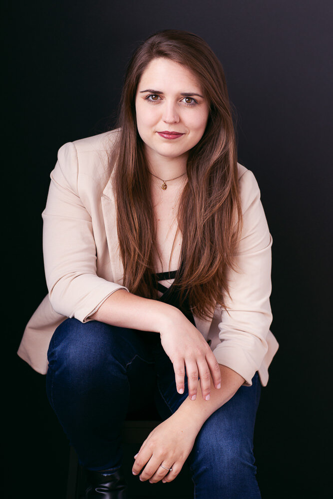 woman with long dark hair in jeans and beige blazer