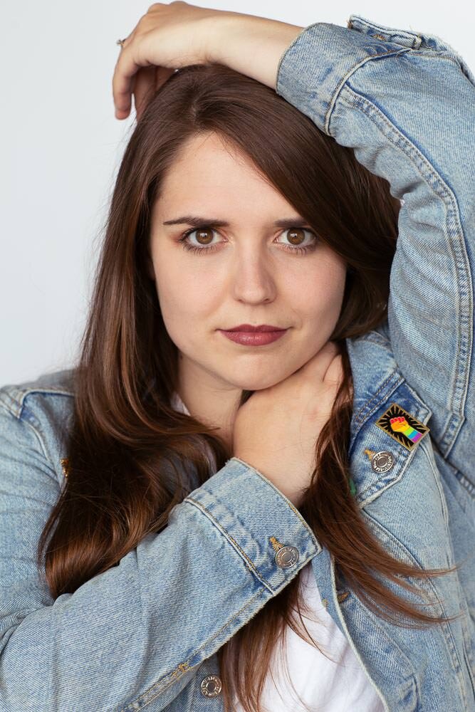 woman in denim jacket with pride pin