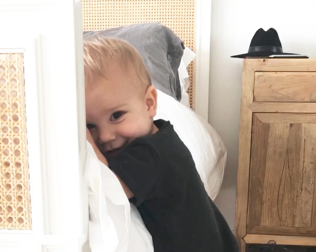 Baby leaning against the bed