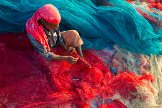 A fisherman in Kerala, India, repairs nets on a beach. Plastic pollution can damage and clog nets, but now fishermen are fighting back. PHOTOGRAPH BY FRANK BIENEWALD, GETTY IMAGES