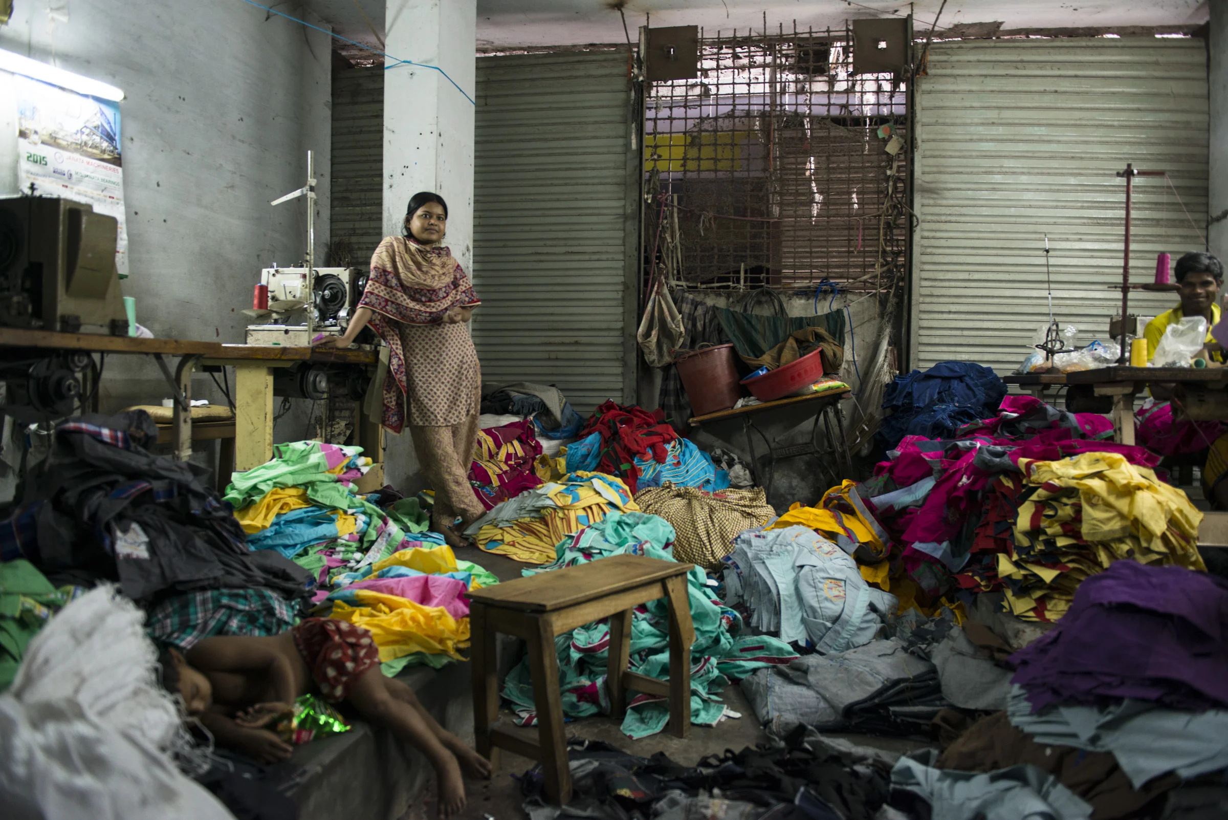 A female garment worker stands amidst children clothes. Due to a lack of child care facilities most young children spend their time with their mother at the workplace. Picture: Claudio Montesano Casillas.