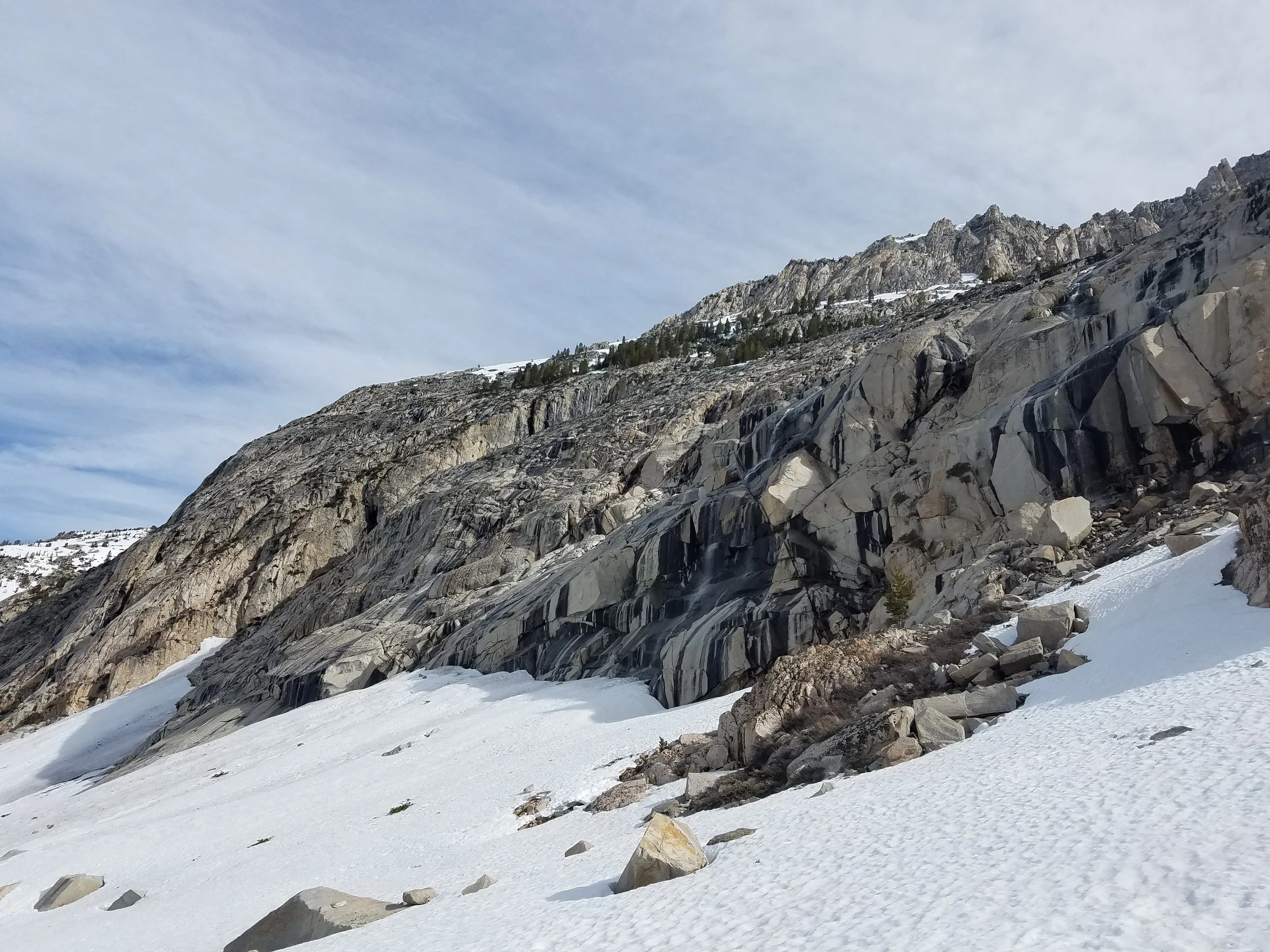 Many waterfalls cascading down the canyon walls, the water disappearing under the snow.