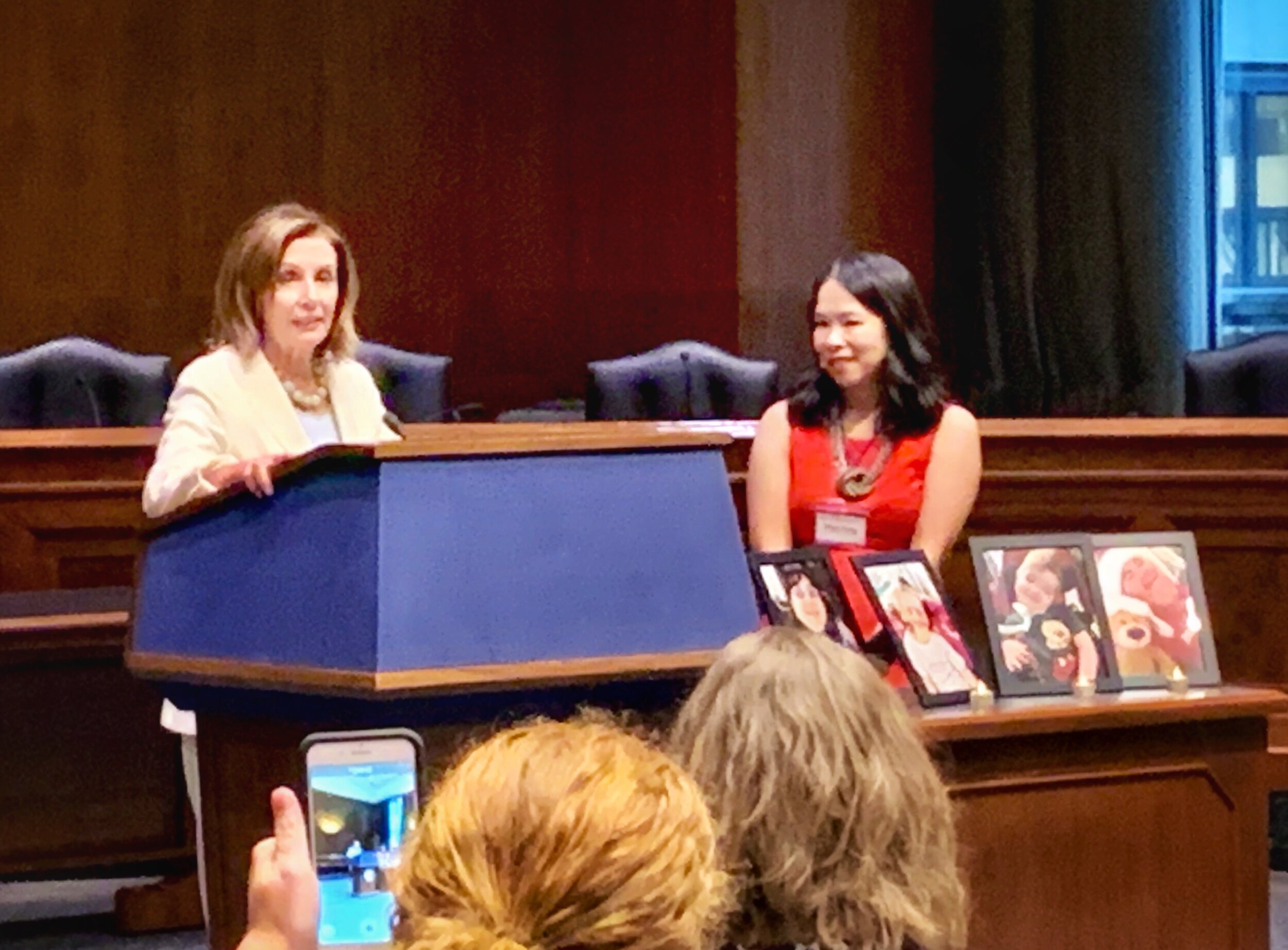  The Speaker of the House stands at a podium while a Little Lobbyists founder looks on. 